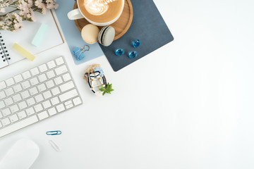 Styled stock photography navy blue office desk table with blank notebook, keyboard, macaroon, supplies and coffee cup. Top view with copy space. Flat lay.