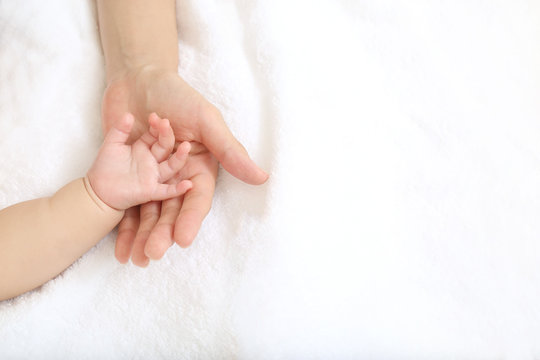 小さな赤ちゃんの手を母の手で包むイメージ