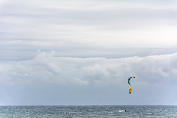 kitesurfers on the sea under an enormous sky.