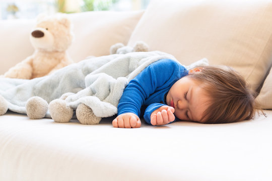 Sleepy toddler boy napping in the afternoon on a sofa