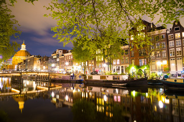 Beautiful night in Amsterdam. Night illumination of buildings and boats.