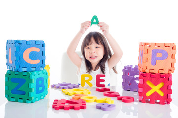 Little asian girl playing alphabet toy over white background