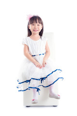 Little asian girl in white dress sitting on chair and smiles