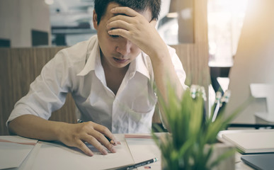 Stressed male designer sitting at desk in  office