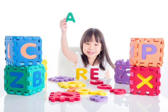 Little Asian Girl Playing Alphabet Toy Over White Background