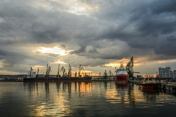 Boat waiting to be loaded with Cranes at sunset.