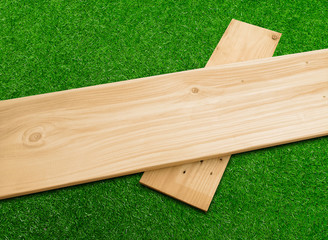 Wooden plank on a green grass background