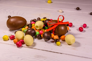 Chocolate easter eggs and multicolored candies on wooden table