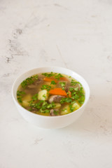 Soup with meat, potatoes and carrot. Beef soup in a white bowl, copy space