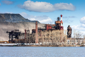 Industrial plant near the lake against the backdrop of a huge dump