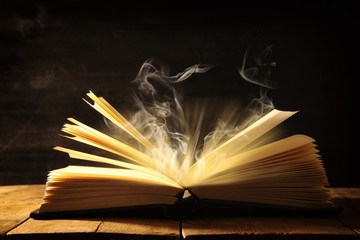 image of open antique book over wooden table.