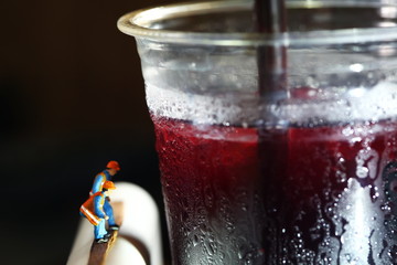 Chilled fruit juice in plastic cup and miniature figure model scene.