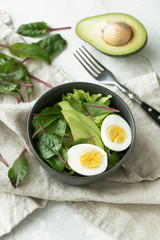 Healthy vegan food. Bowl with salad, avocado and egg, top view. Diet food concept.