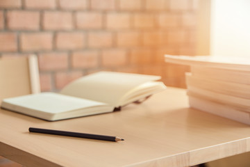 Pencil, book and glasses on table with light background sunset.Education concept