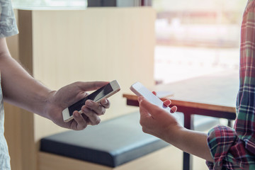 Close up of men and  woman hands holding touching mobile phone with blank copy space for your text message in cafe  with light Sunset,Vintage tone.Selective focus