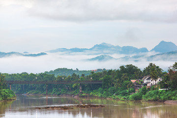 Nam Khan (Khan River) and Old Bridge Beautiful landscape in Luang Prabang. Behind the mountains and morning mist.