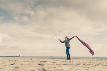 Happy woman jumping with scarf on beach