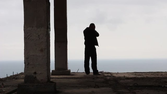Mature man in sorrow. Silhouette of a sad man standing on the edge of a tall building