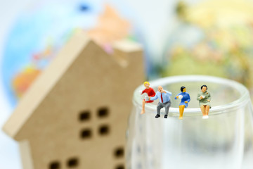 Miniature people: Businessman and woman reading newspaper and sitting on book  using as education or relax business  concept.