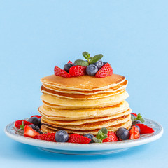 Pancakes with berries on a bright pastel background