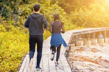 Young asian couple running on wooden bridge in the morning,helping and relaxing concept.