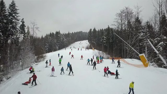 Many skiers and snowboarders descend down the mountain slope
