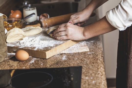 Female hands cut off piece of dough