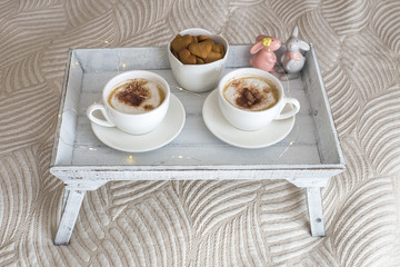 two cups of coffee on the table and cookies in the shape of a heart, two rabbits and a garland