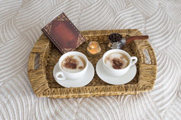 two coffee mugs on the table, a book and a candle