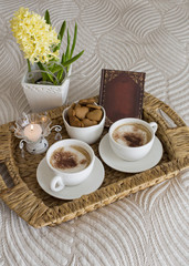 Fototapeta na wymiar two coffee mugs on the table, a hyacinth, a book and a candle