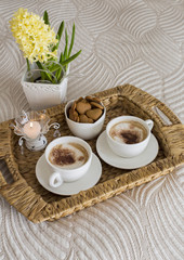 two coffee mugs on the table, a hyacinth and a candle