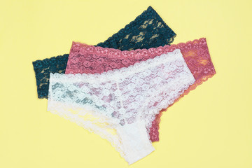 Set of beautiful lace panties on yellow background