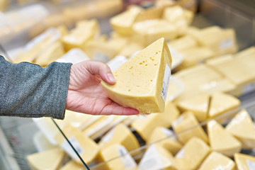 Hand buyer with piece of cheese in store