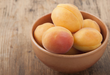 Apricots in a clay bowl on a wooden table