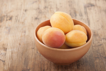 Apricots in a clay bowl on a wooden table