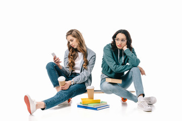 african american girl sitting sad while friend using smartphone isolated on white