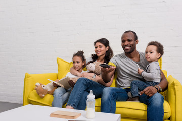 happy young family watching tv together on couch