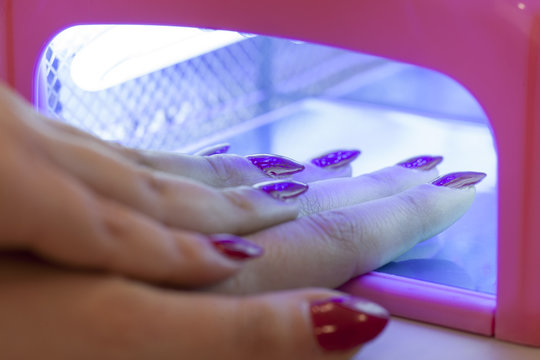 Woman drying her nail polish with uv lamp