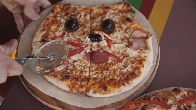 Top view of a person slicing a tasty pizza into slices with a pizza cutter. 4K