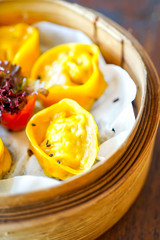 Prawn gluten free dumplings. Chicken curry steamed dumpling.  A hand with chopsticks holds a piece. Wooden table background in a restaurant. Traditional Chinese cuisine. Closeup view with copy space