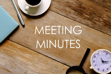 Top view of a cup of coffee,notebook,pen,magnifying glass and clock on wooden background written...