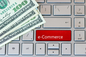 e-commerce Red Button on laptop keyboard with dollar banknotes. Top View