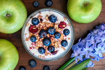 Close-up of a bowl with muesli with berries and yogurt. Green apples. Concept of healthy eating, vegetarian food.