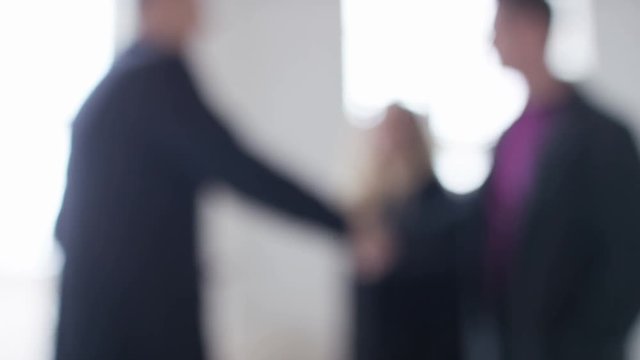 Wide shot of blurred background of people shaking hands during real estate viewing