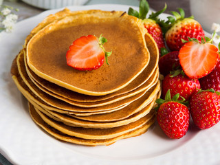 Stack of oatmeal flour pancakes with strawberries on white dish