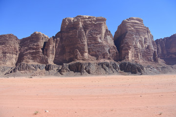 Fahrspuren im Sand vor Felstürmen im Sand im Wadi Rum in Jordanien 