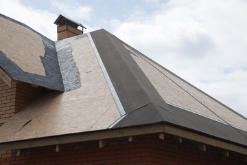 Roof is covered with plywood Boards with a Chimney of brick on the sky background. Installation of Waterproofing