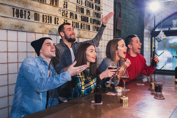 Group of young beautiful friends watching TV and cheering for th