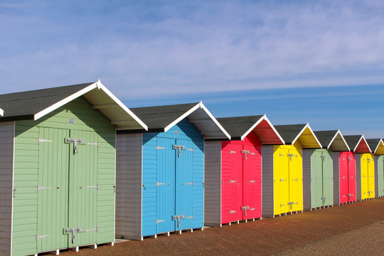 a row of colourful beach huts, against a blue sky