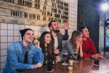 Group of young beautiful friends watching TV and cheering for th